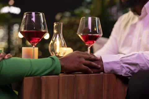 Close up of couple joining hands during romantic rooftop restaurant date Fotos Stock