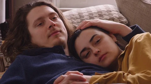 Close up couple lying down on a couch relaxing and watching TV. Stock Footage 129897672