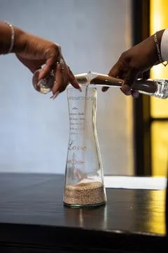 Close up of couple pouring unity sand into glass vase during wedding ceremony Stock Photos