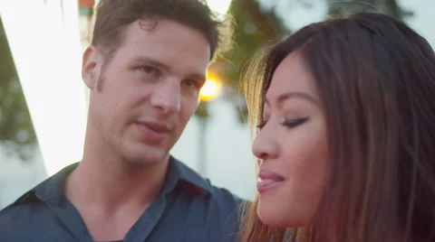 Close up of a couple talking in front of a carnival ride Stock Footage 55608656