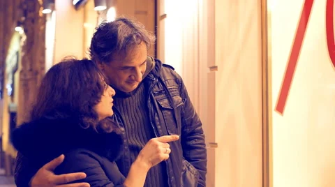 Close up of a couple walking down the street at night and go window shopping Stock Footage 60404502