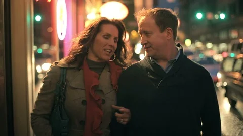 A close up of a couple walking down the street at night window shopping Stock Footage 98379380