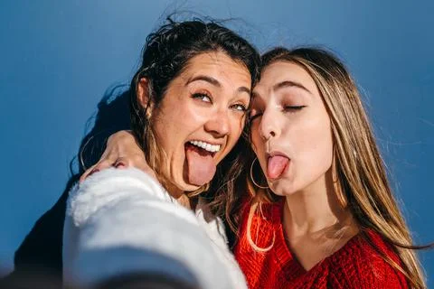 Close-up of a couple of young girls sticking out their tongues while taking a Stock Photos