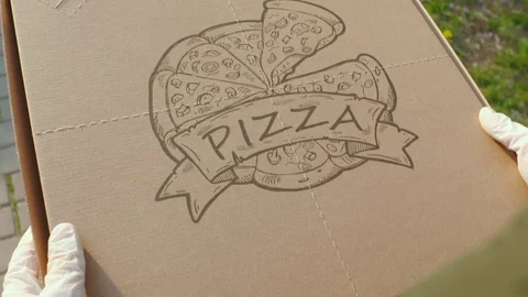 Close-up of courier hand in gloves carry box of pizza along street 動画素材 129875595