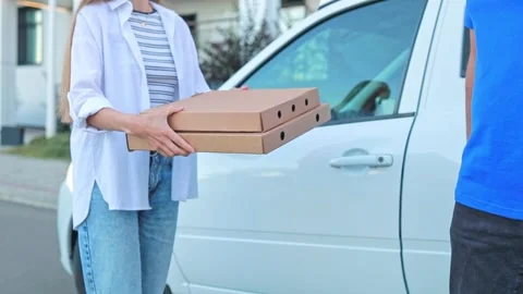 Close-up of a courier handing pizza boxes to a woman. Food delivery, online Stock Footage 318942715