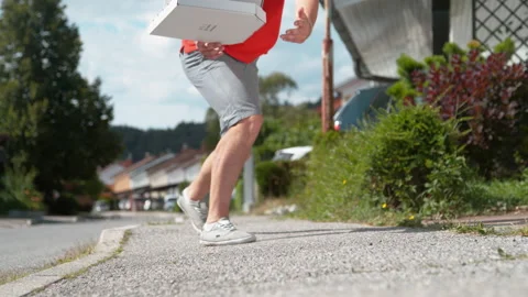 CLOSE UP: Courier trips and falls to asphalt pavement along with a few parcels. Stockbeeldmateriaal 140039055