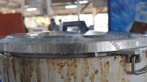 Close-up on covered pot with boiling water over in-ground fire pit for the makin 스톡 동영상 87393893
