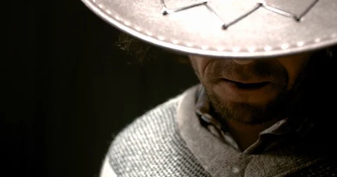 Close up of a cowboy in a hat putting a cigar in his mouth, low lighting, 4k Stock Footage 129322162