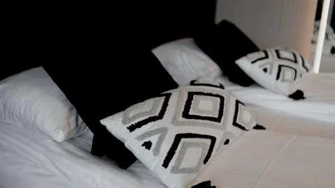 Close up of cozy bed with decorative geometric pattern pillows and white sheets. Stock Footage 340341971