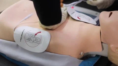 Close up CPR training using and an AED and bag mask valve on an adult training Stock Footage 280010892