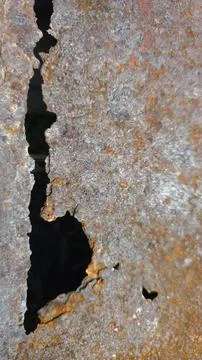 Close-up of cracked rusty metal surface with corroded hole, abstract industri 스톡 사진
