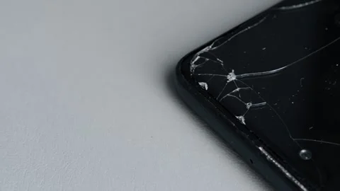 Close-up cracked screen protector on black smartphone corner background. Damaged Stock Footage 344846640