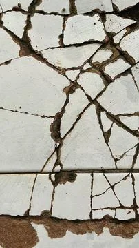 Close-up of cracked white ceramic tile surface with damaged grout lines 库存照片
