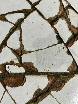 Close-up of cracked white ceramic tile surface with damaged grout lines Foto stock