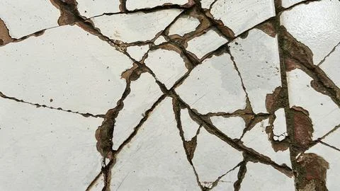 Close-up of cracked white ceramic tile surface with damaged grout lines Stock Photos