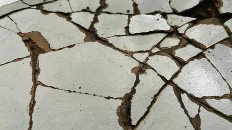 Close-up of cracked white ceramic tile surface with damaged grout lines 库存照片