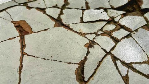 Close-up of cracked white ceramic tile surface with damaged grout lines Stock Photos