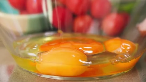 Close-up of cracking eggs into a transparent glass bowl. Raw egg contents Stock Footage 335712714