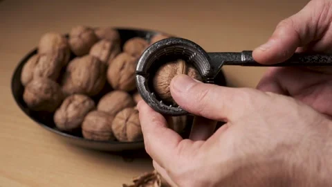 Close Up of Cracking Walnut with Nutcracker on Wooden Table Video stock 331531198