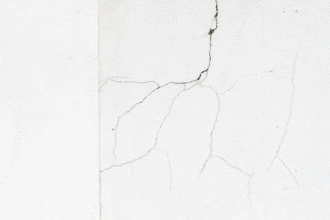 Close-up of cracks on a white concrete wall showing signs of aging, weatherin Stock Photos