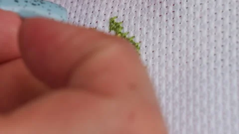 Close Up Crafter Passing Needle with Green Thread on Cross Stitch Stock Footage 328354850