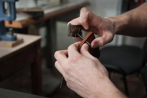 Close-up of a craftsman's hands and the process of hand-stitching a leather.. Stock Photos