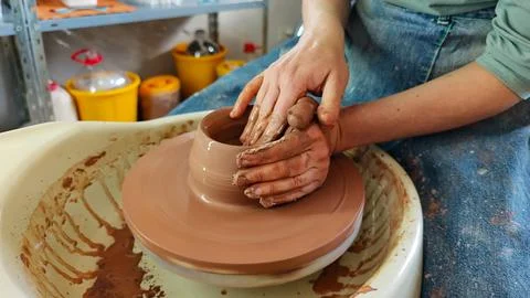 Close-up of a craftsman's hands skillfully shaping a piece of pottery from .. Stock Photos