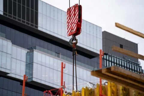 Close up of crane hook and chain at construction site near modern building Foto stock