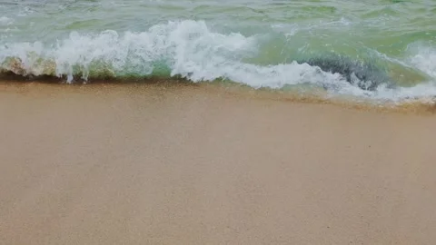 Close-up of crashing emerald sea waves and white foam on sandy beach Stock Footage 338194022