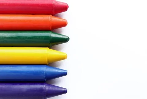 Close up of crayons lined up in rainbow isolated on white background. Stock Photos