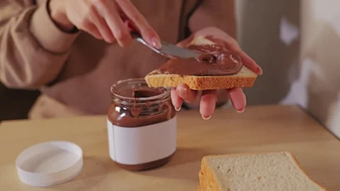 Close Up Of Creamy Hazelnut Spread Being Smoothed Across A Slice Of White Bread Stock Footage 340257984