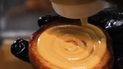 Close-up of creamy sauce being applied in a spiral onto a baked food item. Stock Footage 331633181