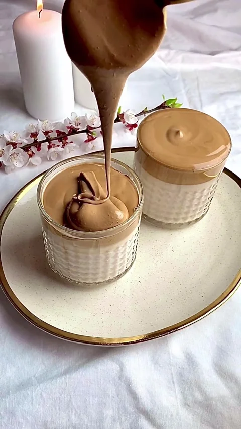 Close-up of creamy whipped dalgona coffee being poured into a glass of milk. Stock Footage 344016136