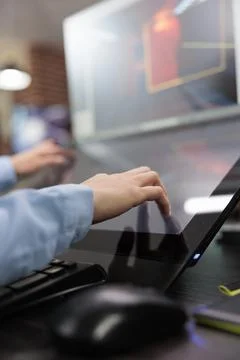 Close up of creative game creator hands on multiple modern displays while Stock Photos