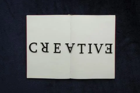 Close up to CREATIVE lettering over blank notebook at blue navy background 스톡 사진