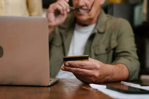 Close up of credit card while elderly male online shopping from home Stock Photos