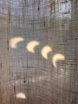 Close-up of crescent-shaped solar light projections cast on a textured line.. Stock Photos
