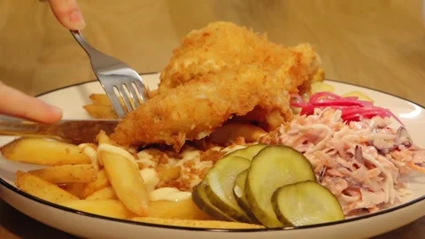 Close-up of crispy breaded fish served with golden fries topped with sauce Stock Footage 331313950