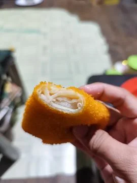 Close Up of Crispy Breaded Fried Snack Held by Hand Showing Layered Filling Stock-Fotos