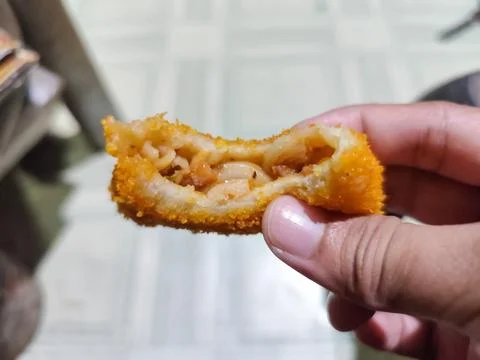 Close Up of Crispy Breaded Fried Snack Held by Hand Showing Layered Filling Stock Photos