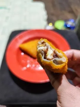 Close Up of Crispy Breaded Fried Snack Held by Hand Showing Layered Filling Stock Photos