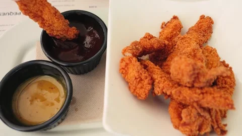 A close-up of crispy chicken nuggets served on a table with homemade sauces Stock Footage 334713371