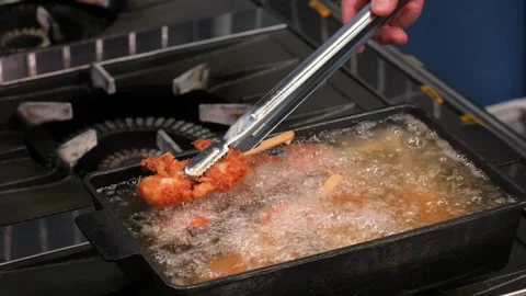 Close-up of Crispy Chicken Pieces Sizzling in Boiling Oil in a Deep Fryer Stock Footage 337440622