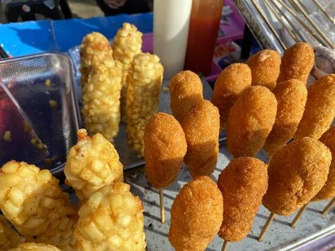 A close-up of crispy corn dogs and potato crusted hot dogs on stick, Stock Photos