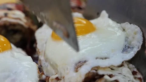 Close-up of Crispy Fried Eggs with Runny Yolks on Savory Topping Stock Footage 331956487