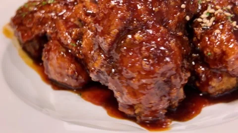 Close-up of crispy, glazed chicken pieces with sesame seeds and herbs slow mo Stock Footage 321670060