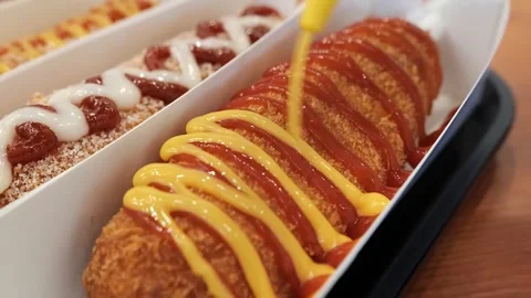 Close-up of Crispy Korean Corn Dogs with Ketchup and Mustard Drizzle, Popular St Stockbeeldmateriaal 331955794