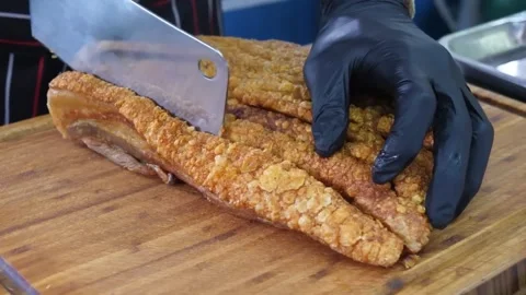 Close-up of Crispy Roast Pork Belly (Siu Yuk) Being Sliced on a Wooden Cutting B Stock Footage 338211850