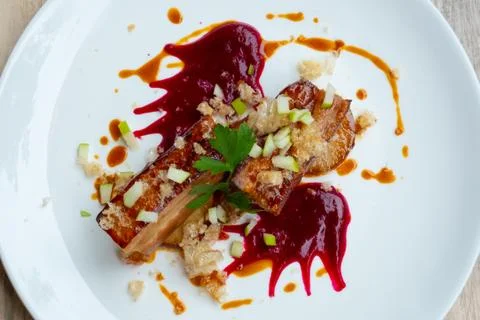 Close up of crispy slow cooked pork belly in beetroot sauce and apple Stock Photos