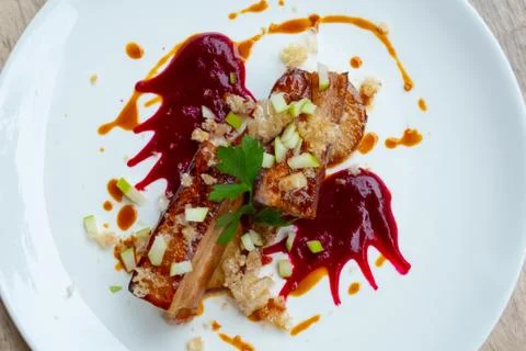 Close up of crispy slow cooked pork belly in beetroot sauce and apple Stock Photos